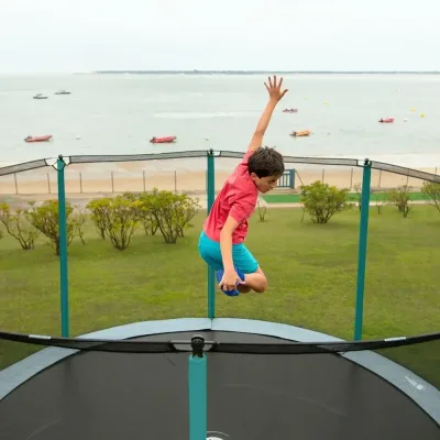 Niño saltando en una cama elástica frente al mar